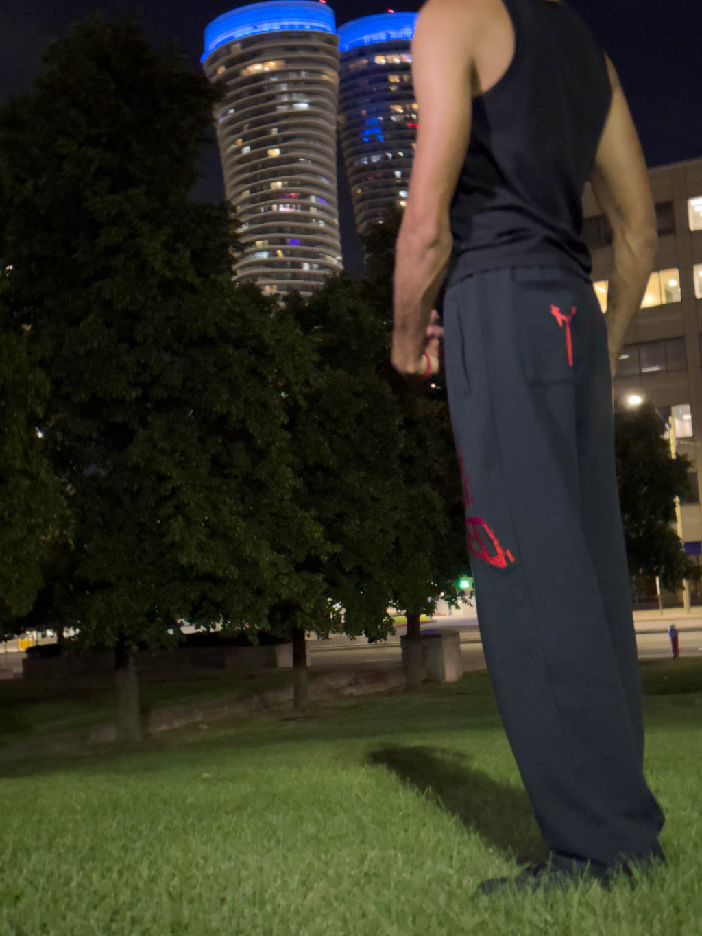 man standing in front of two towers on the ground wearing baggy blac ksweatpants with the ARIEL brand logo on the back pocket